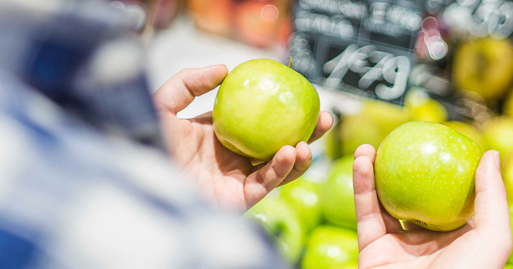 Ein Mann h&auml;lt zwei frische gr&uuml;ne &Auml;pfel in der Hand.